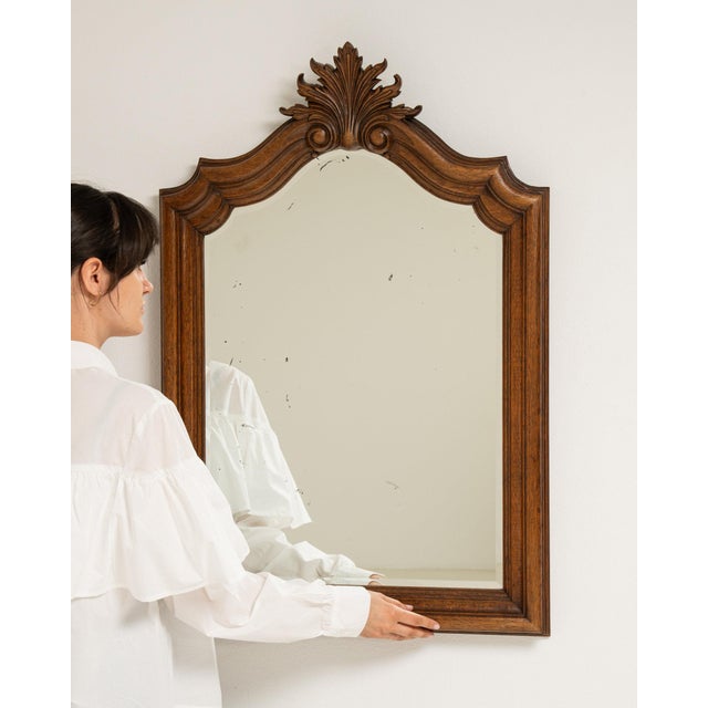 Here is a mirror, its natural wood frame with carved crest, arched the first thing to catch the eye. It was made in France...