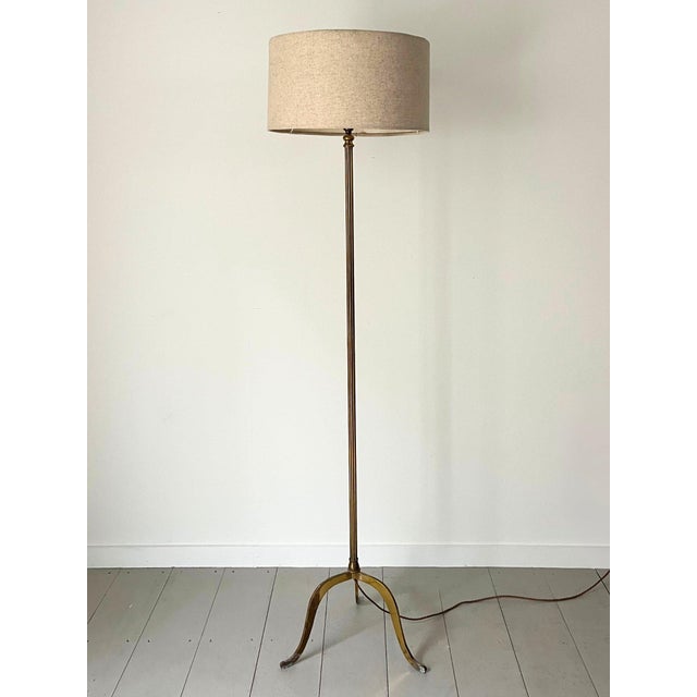An understated and elegant 20th century brass floor lamp, c. 1950s. This mid century vintage standing lamp has a slim...