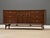 A mid century modern walnut dresser made by Broyhill Brasilia with swooping sculpted door pulls and matching polished...