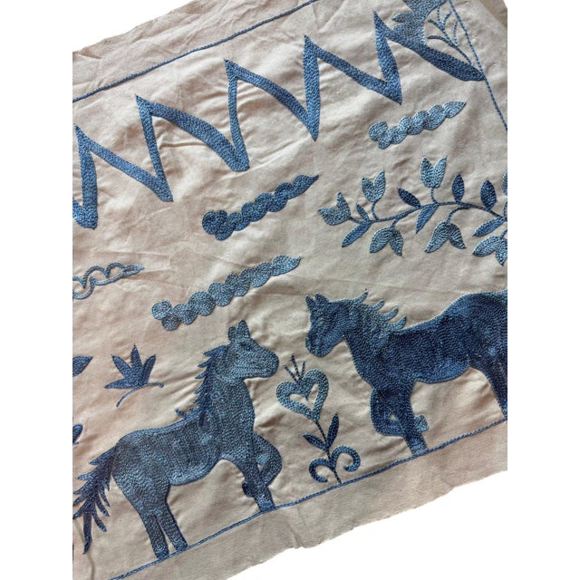 Hand-embroidered Suzani panel from Uzbekistan, worked in fine floss on a cream cotton ground. Three blue horses move...