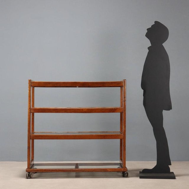 Central bookcase with wheels, beech wood, shelves with slats and clear glass. This piece is attributed to the mentioned...