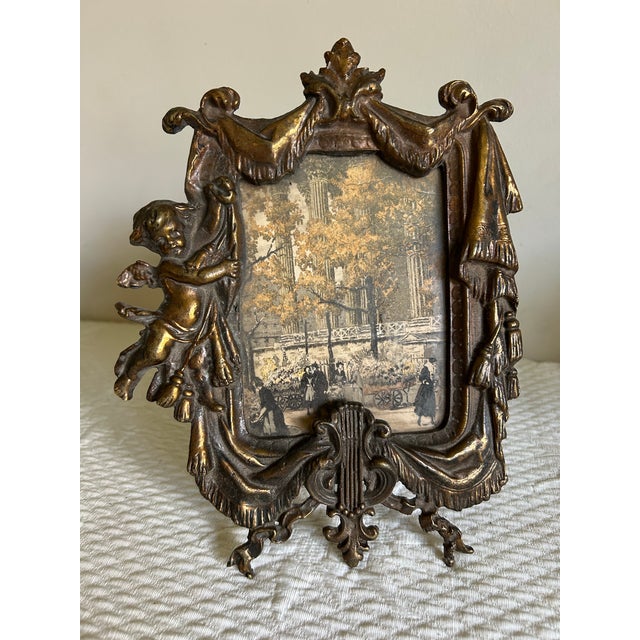 Antique Victorian bronze picture frame. Ornate decor, features Cupid and a harp. Comes with glass. Opening fits a 4 x 6”...