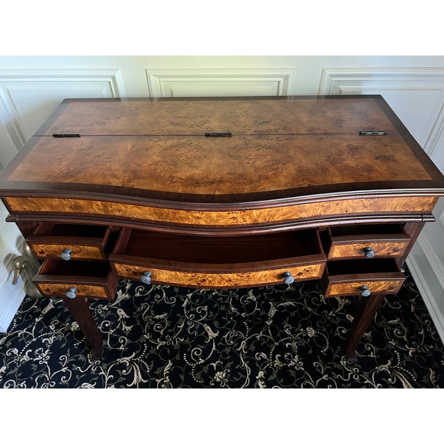 A bowfront Campaign desk, the flip top enclosing a fitted interior and a leather writing surface, with five drawers...