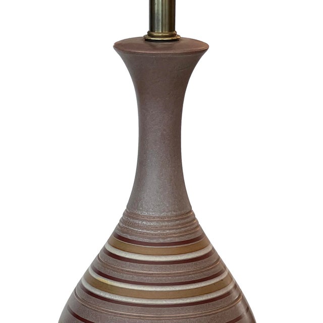 each striking lamp with long flaring neck above an ovoid body decorated with ivory, brown and ochre perimeter stripes on a...