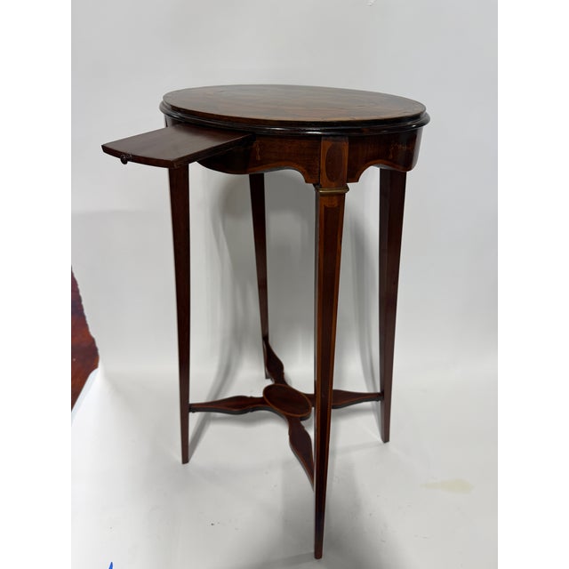 A refined Edwardian inlaid tea table of elegant small scale, designed with an oval top, single pull slide shelf, shaped...