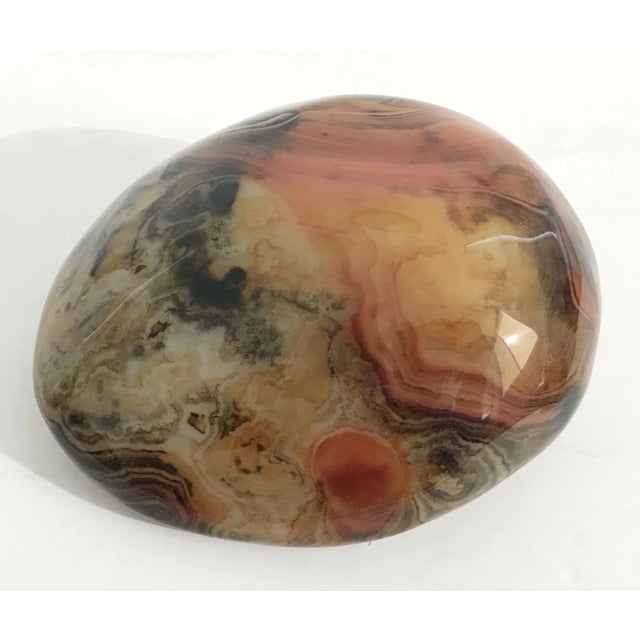 Hand polished agate onyx stone paperweight in black, brown, and red intricate layered patterns Measures: length 5 inches,...