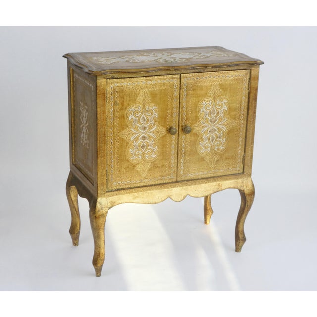 Vintage Florentine chest with two doors in golden colours with white made out of wood. The curved serpentine legs give a...
