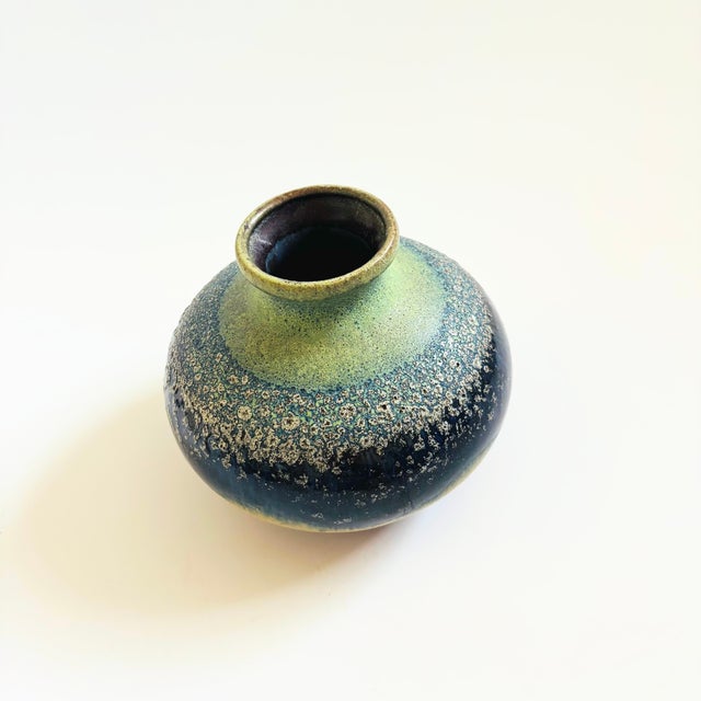 A vintage mid century pottery vase with a textured lava glaze. Blue, light green, tan, and brown glazes. No marking on the...