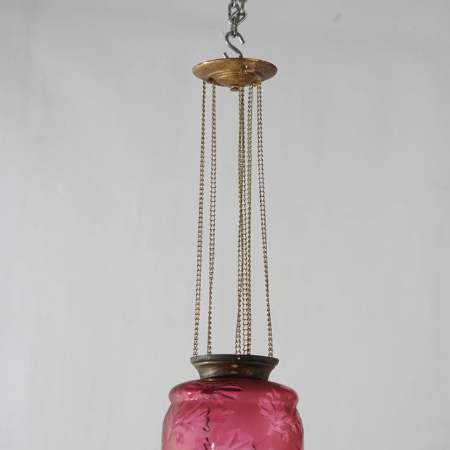 An antique Victorian hanging pendant hall light offers brass frame with cut to clear cranberry glass shade with flowers,...