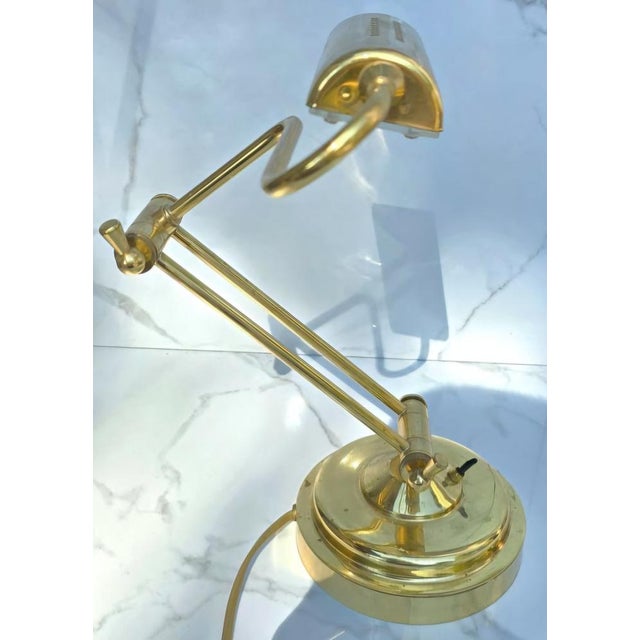 Elegant adjustable lamp crafted in polished brass, featuring a clean modernist silhouette. The design combines a weighted...