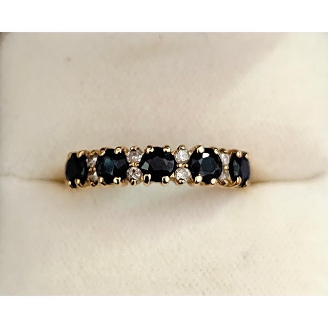 A stunning garter-style ring featuring five deep blue sapphires and pairs of brilliant-cut diamonds set between each...