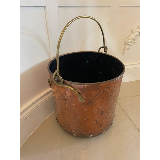 Antique Victorian quality brass and copper coal bucket having a swing handle, brass rivets and a circular shape...