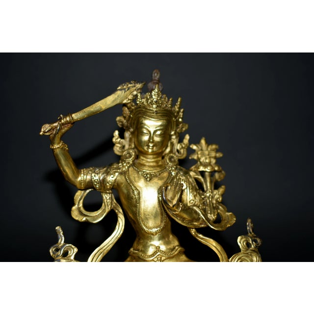 A beautiful, brightly gilded bronze statue of Tibetan Bodhisattva Manjushree. Seated in vajrasana on double lotus base,...