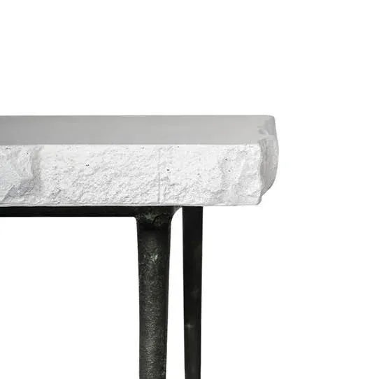 A handsome low table with a squared stone top with a natural rough hewn edge over elegant tapering metal legs, crafted...