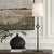 With Its Striking Forged Cast Iron Base In Rustic Bronze With Noticeable Hammered Texture, The Puncture Table Lamp...
