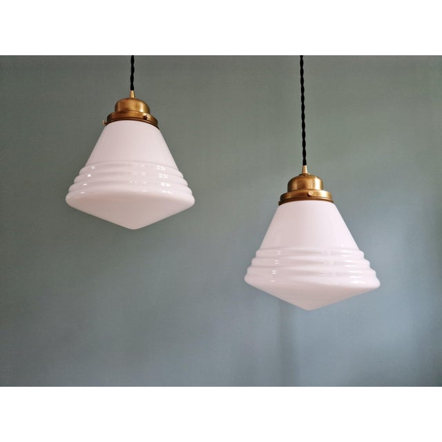 Art deco philips pendant light with a white opaline glass conical globe and a brass mount, 1930s. the pendant light has...