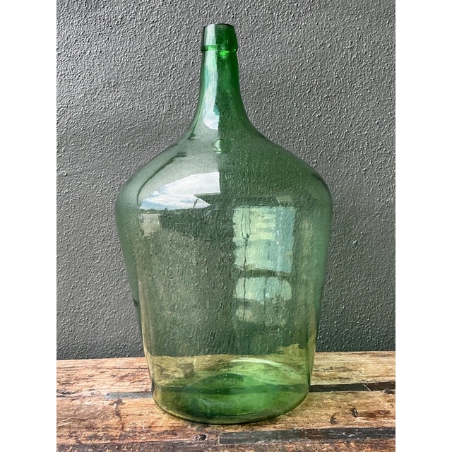 This vintage green glass demijohn bottle exemplifies the quiet beauty of mid-20th-century European utilitarian design,...