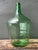 This vintage green glass demijohn bottle exemplifies the quiet beauty of mid-20th-century European utilitarian design,...