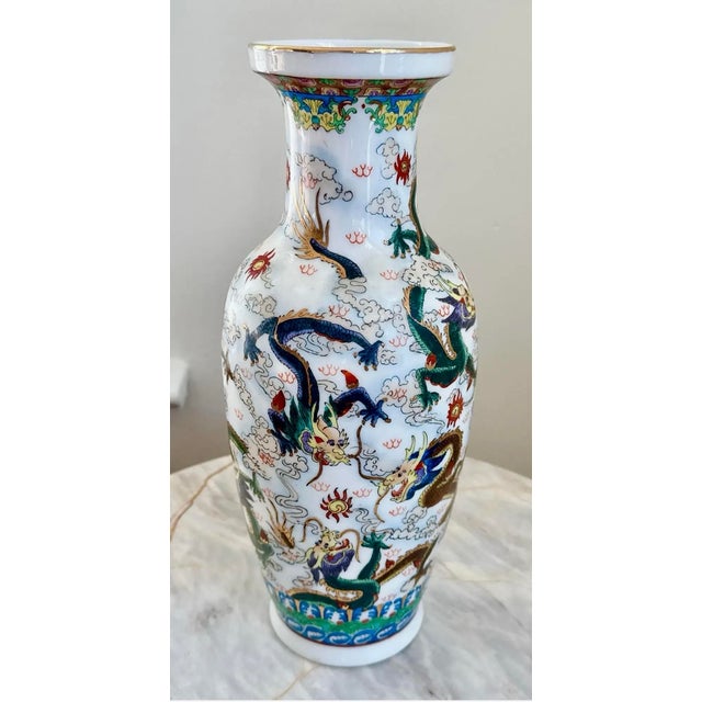 Vintage hand-painted Chinese porcelain dragon vase featuring colorful dragons and gilt accents against a white background....
