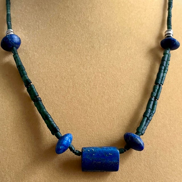 Distinctive beaded necklace handcrafted with striking deep blue lapis lazuli and cylindrical green serpentine. The center...
