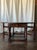 This charming vintage drop-leaf coffee table features a rich, dark wood finish and a classic oval top with hinged gate-leg...