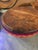 handcrafted, coiled basket with a flat leather lid, featuring vibrant geometric and striped patterns in yellow, red, and...