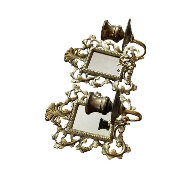Pair of ornate brass mirrored wall candle holders. Velvet backings hold the mirrors in place. Designed to be mounted on a...