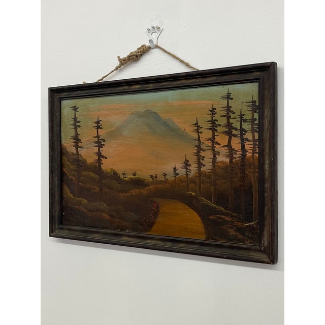 This vintage framed landscape painting depicts a winding path leading through a wooded foreground toward a distant...