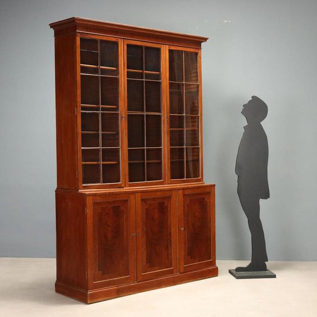 Mahogany bookcase from early 20th century England, featuring an elegant and functional design. The upper section has three...