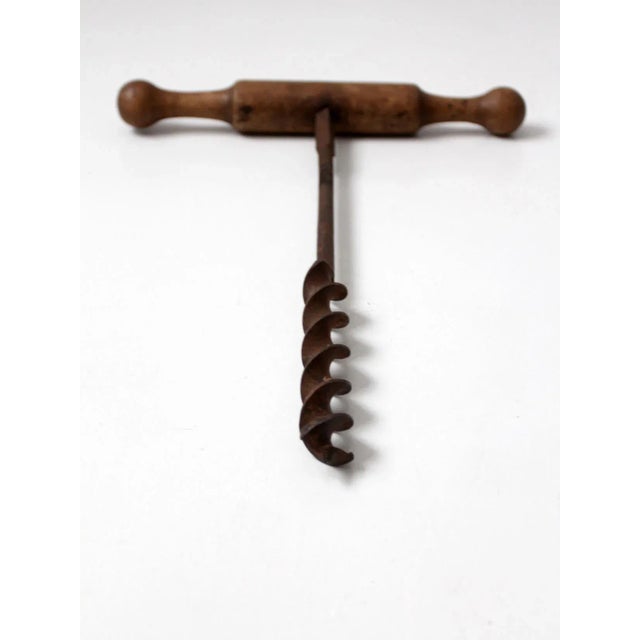 This is an early 20th century antique primitive hand beam auger. It features a wood t-bar handle with iron drill bit.