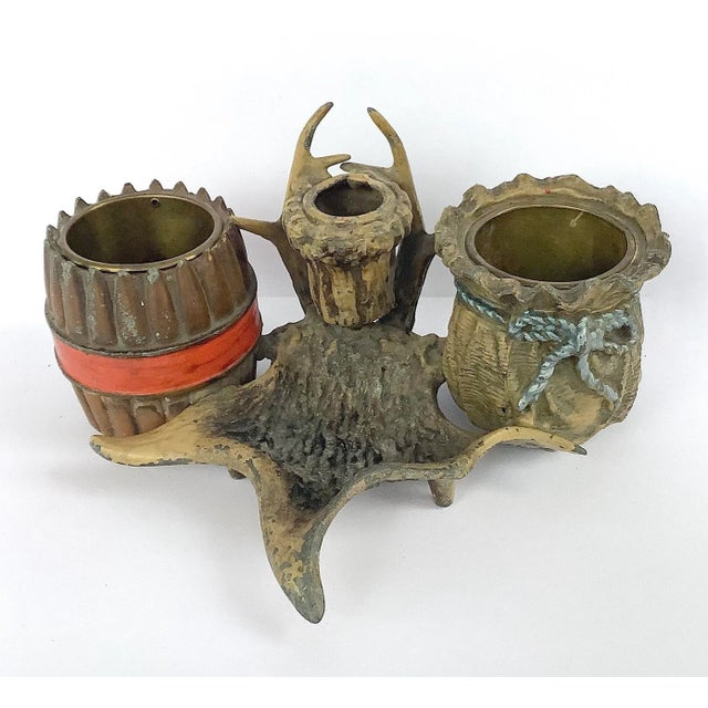 Circa 1930s cast iron pipe/tobacco holder in faux antler with cigar decorated cup on left and basket on right both lined...