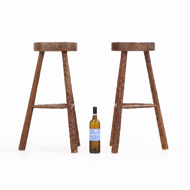 Each stool features a thick, round seat with deep gouge-carved detailing, showcasing expressive handwork and raw...