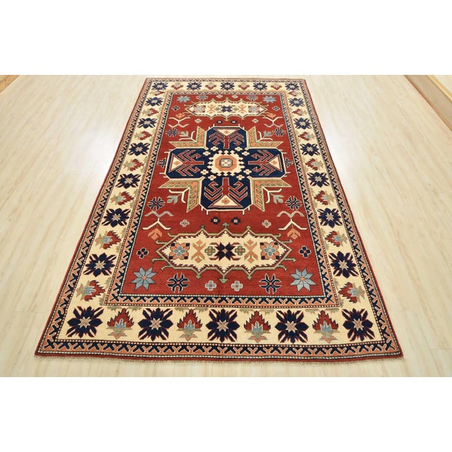 This traditional tribal geometric Caucasian Kazak rug is hand-knotted with an all-wool pile on a cotton foundation. This...