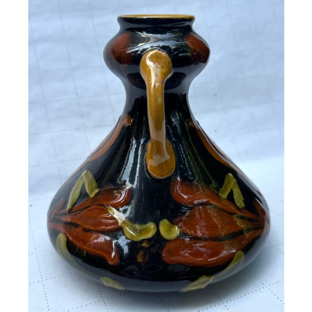 Here we have a vase decorated with raised tulips in oranges and green glaze , mustard interior and handles , 5.25" tall...