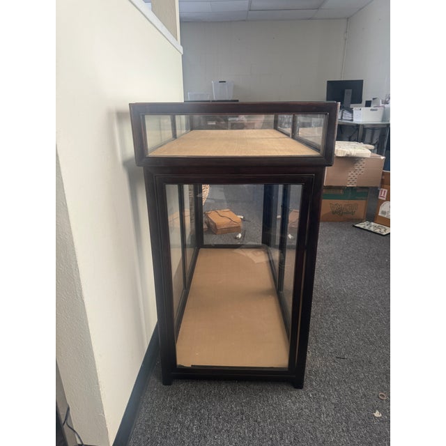 Dark wood and glass Asian display cabinet with an upper glass topped compartment and a lower two door cabinet. The upper...