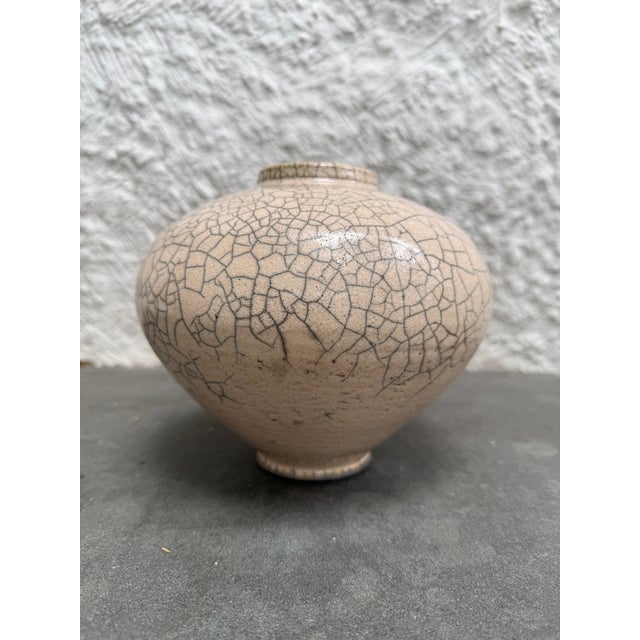 Ovoid Raku Fire glaze vase with an incised signature on the bottom. The color of the vase is a creamy pink with gray...