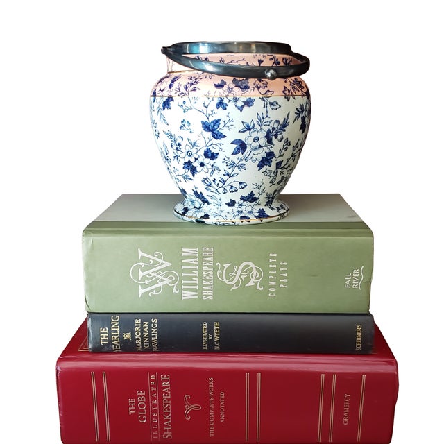 A softly faded antique English flow blue jar featuring a delicate painterly cobalt pattern, accented with a warm peach...