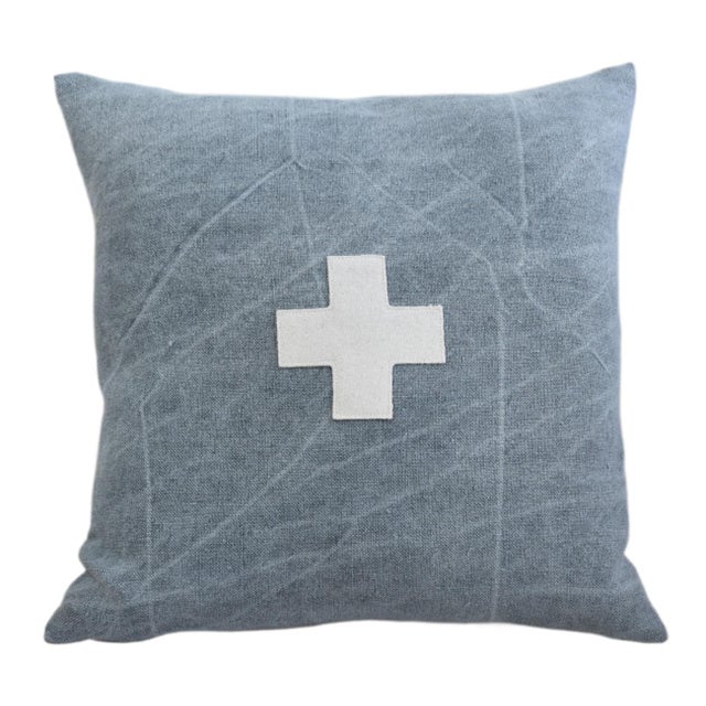 Custom-tailored pillow created from a blue woven cotton/linen textile. Pillow has a cream-colored wool appliqué cross on...