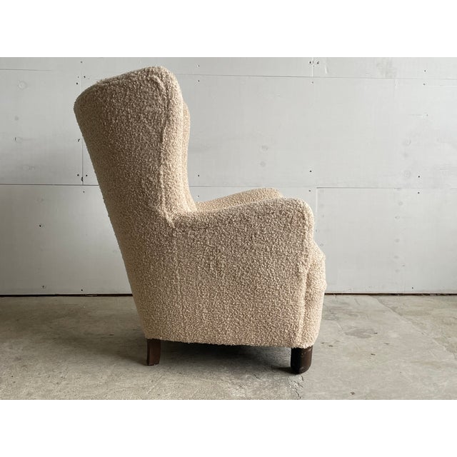 A Danish cabinetmaker wingback lounge chair produced in Denmark circa 1945–1955, newly upholstered in a sand-toned bouclé...