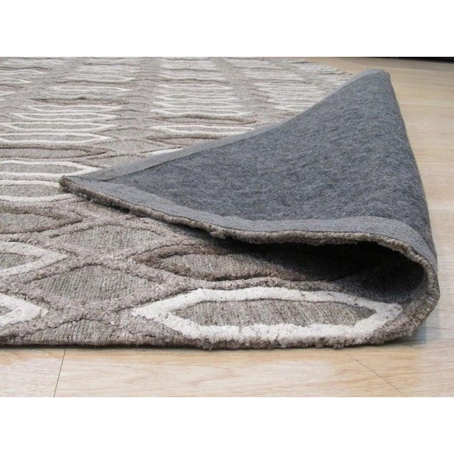 This gray wool rug features a hand knotted pile weave and presents a modern Rabat style design. Crafted in India, this...