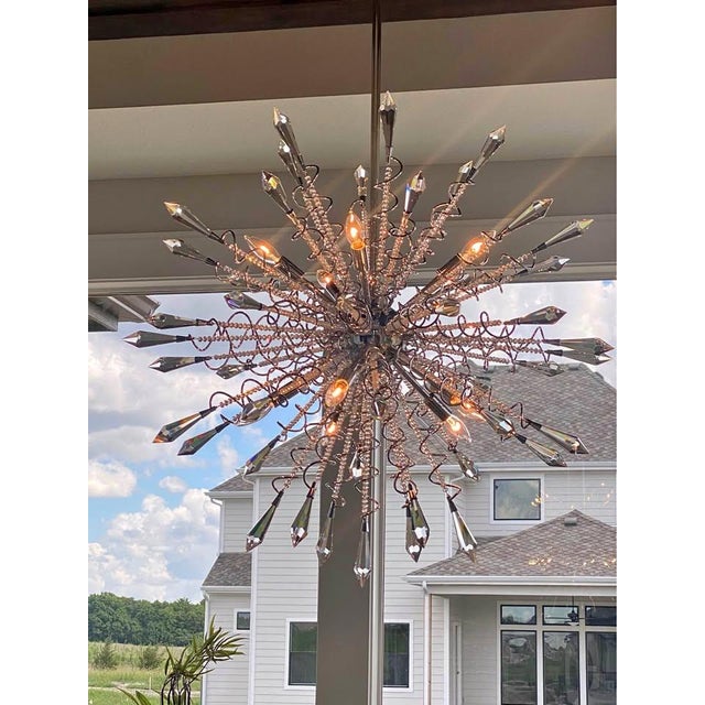 Description: This crystal starburst chandelier, a bold, modern take on the classic Sputnik form. Radial arms extend...
