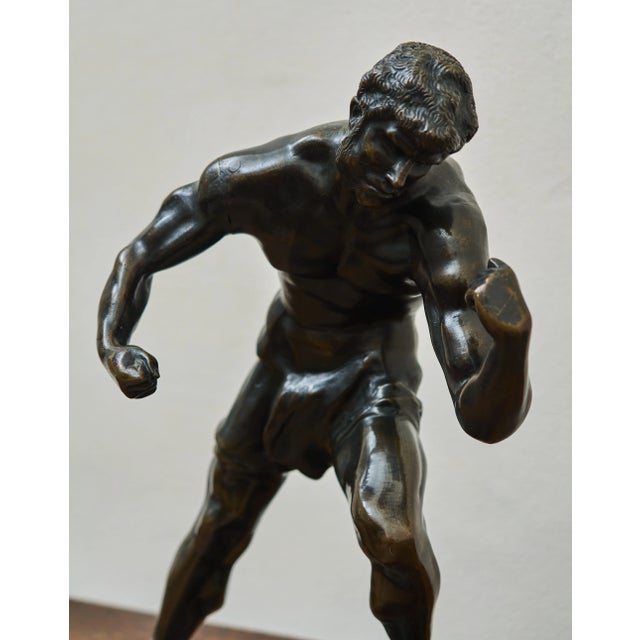Bronze sculpture representing an athletic male figure in a dynamic stance, inspired by the ideals of classical ancient...