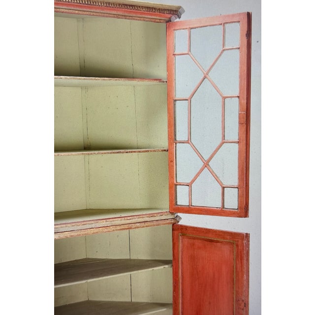 A two-part corner cabinet with a display cabinet top from the late 18th century. Painted in light red with subtle gilding...