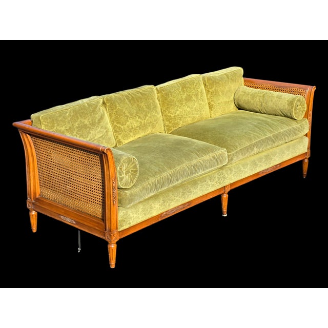 The Schoonbeck Co. Mid-Century French Louis XVI Style Walnut Caned Sofa with Loose Cushions and Bolster Pillows is a...