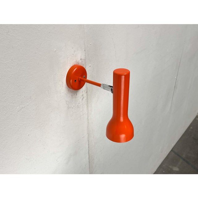 Minimalist wall lights from swisslamps in a unique color. a simple design in a striking orange hue. The light head...