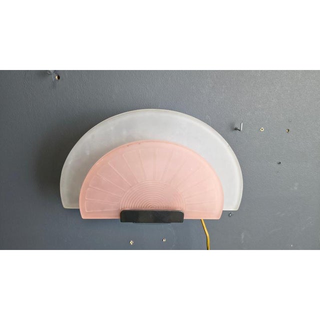 Glass wall sconce by Arteluce. The italian design wall lamp has a matte glass pink and white lamp shade and emit a soft...