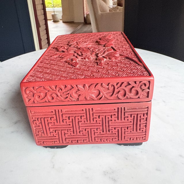 Chinese carved cinnabar lacquer rectangular box, mid-20th century. The lid features a large peony blossom with buds and...