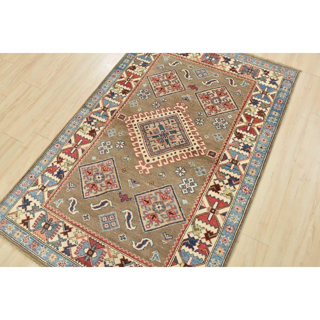 A tribal Caucasian Kazak rug hand-knotted with an all-wool pile on a cotton foundation. This oriental rug features a...