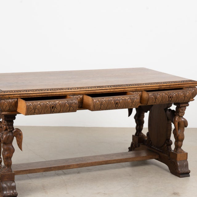 19th century Danish desk, crafted in oak with dramatic hand carved details throughout. Four carved angels or putti form...