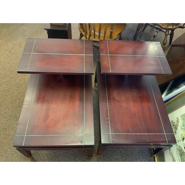 Pair of Mid Century vintage step tables with brass cap feet and line inlay, marked Lane Furniture Company. A standard...